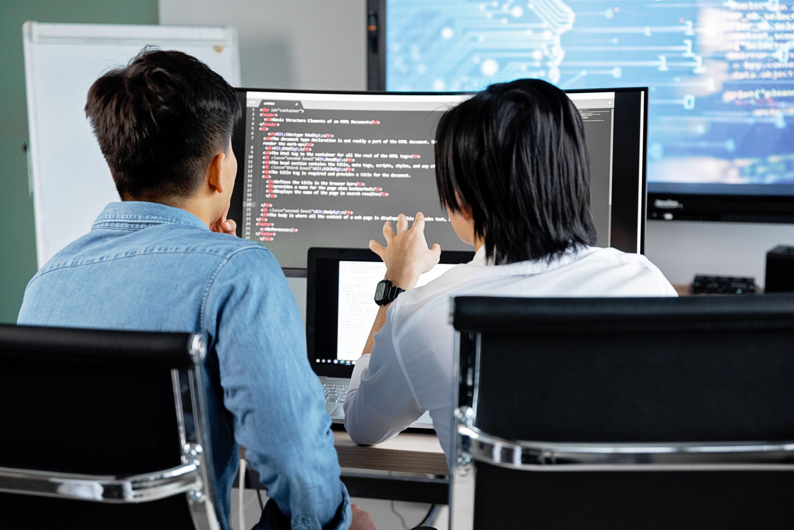 Two developers discussing code together on screen in a modern office