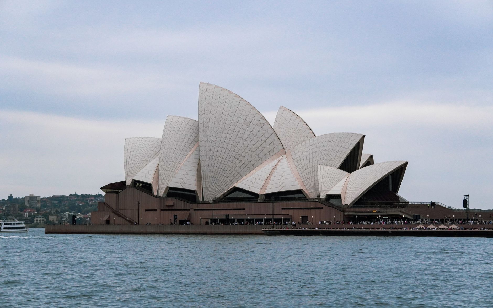 The Sydney Opera House viewed across Sydney Harbour under a soft evening sky.