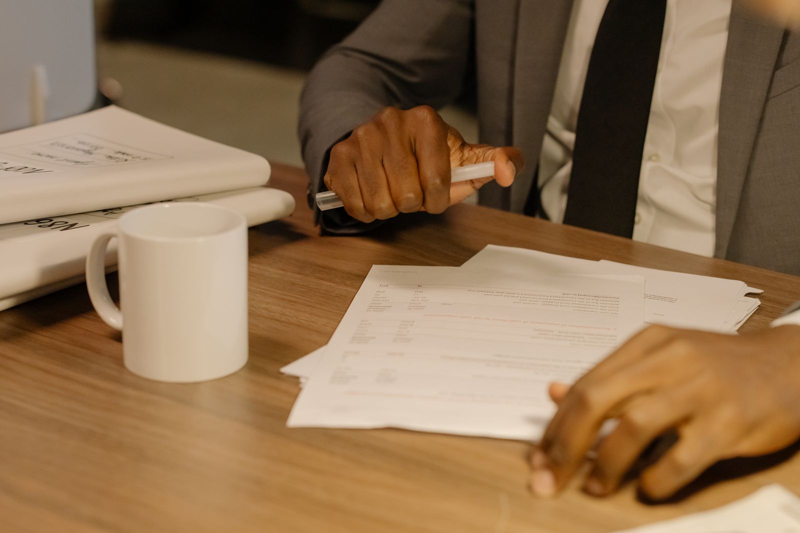 A person holding and reviewing printed documents at a wooden desk, representing a close reading of a draft NIST transition report